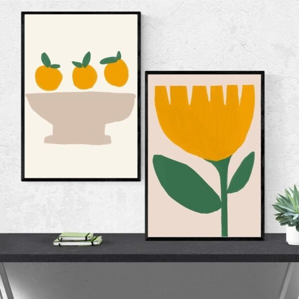 Two framed artworks: one with three oranges in a bowl, the other featuring a large yellow flower with green leaves.
