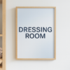 Framed print displaying the text 'DRESSING ROOM' in bold black letters on a light background.