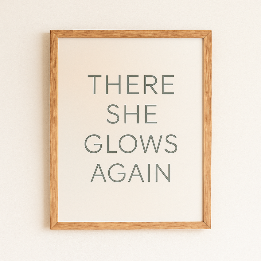 Framed wall art print with the text 'There She Glows Again' in a simple, modern font on a light background.