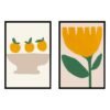 Two framed artworks: one with three oranges in a bowl, the other featuring a large yellow flower with green leaves.